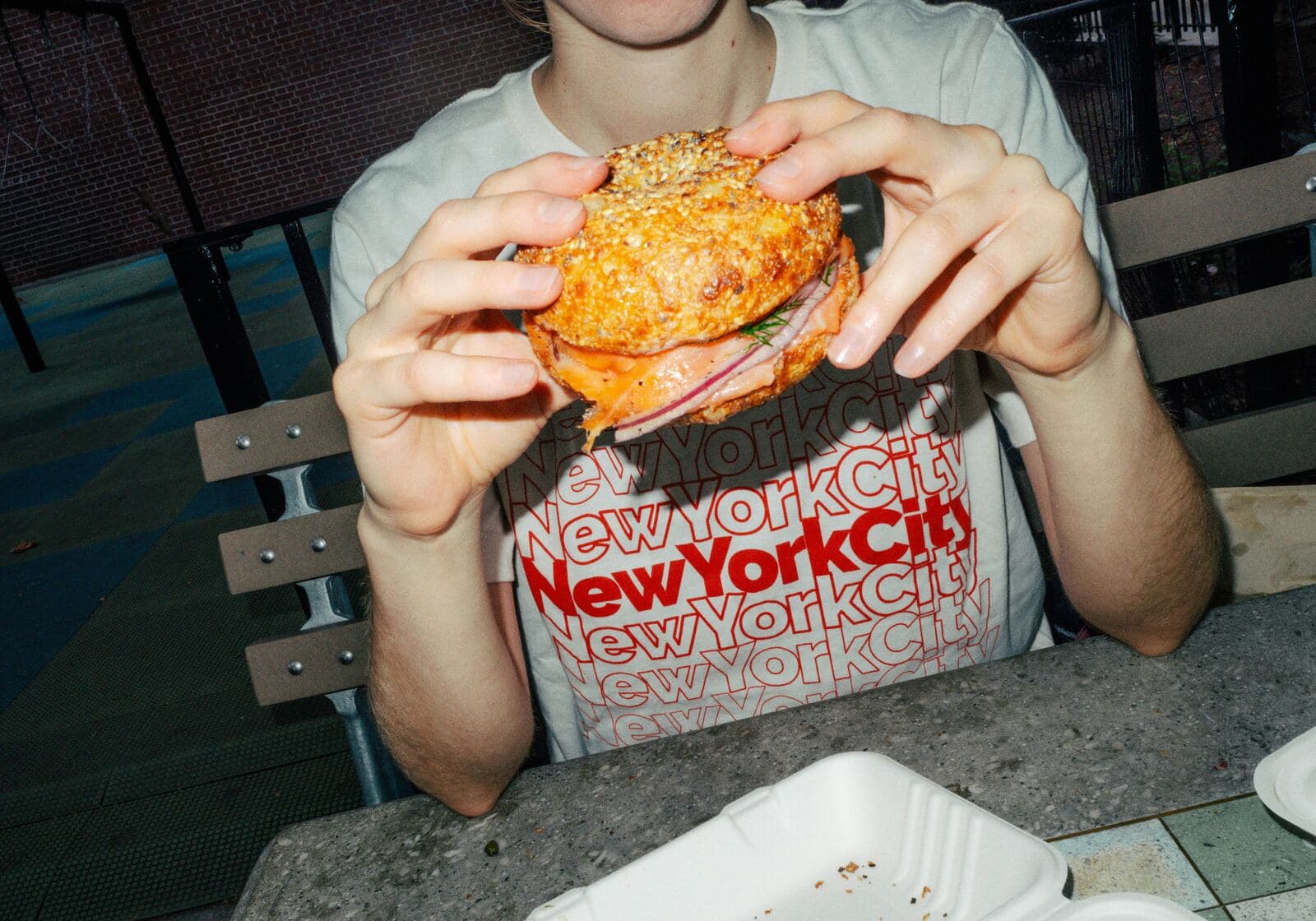 Person enjoying a burger in a New York City shirt